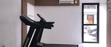 A room with two treadmills, a white ceiling, and a door leading outside.