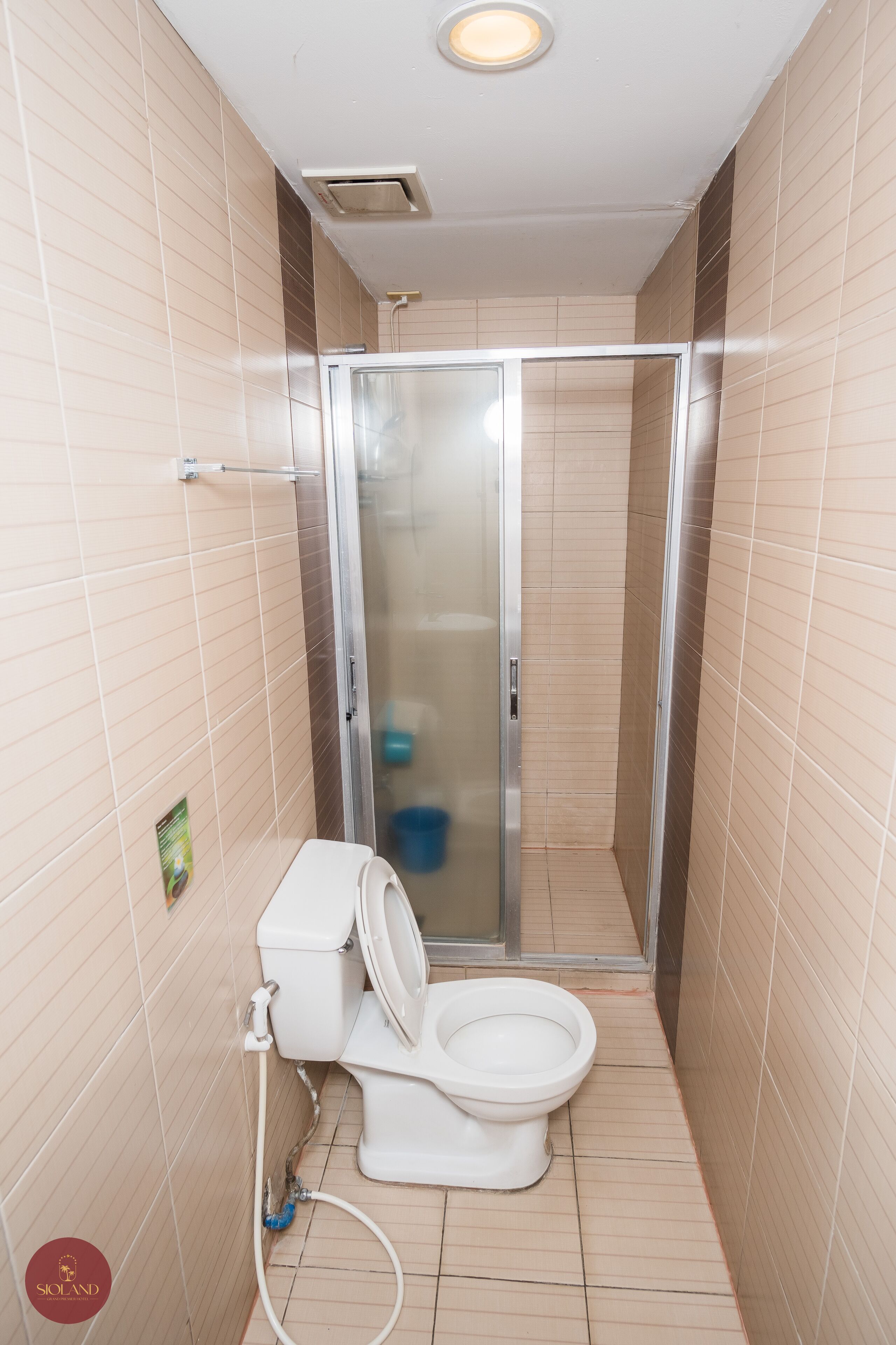 A small bathroom with a toilet, a shower with a glass door, and tiled walls.