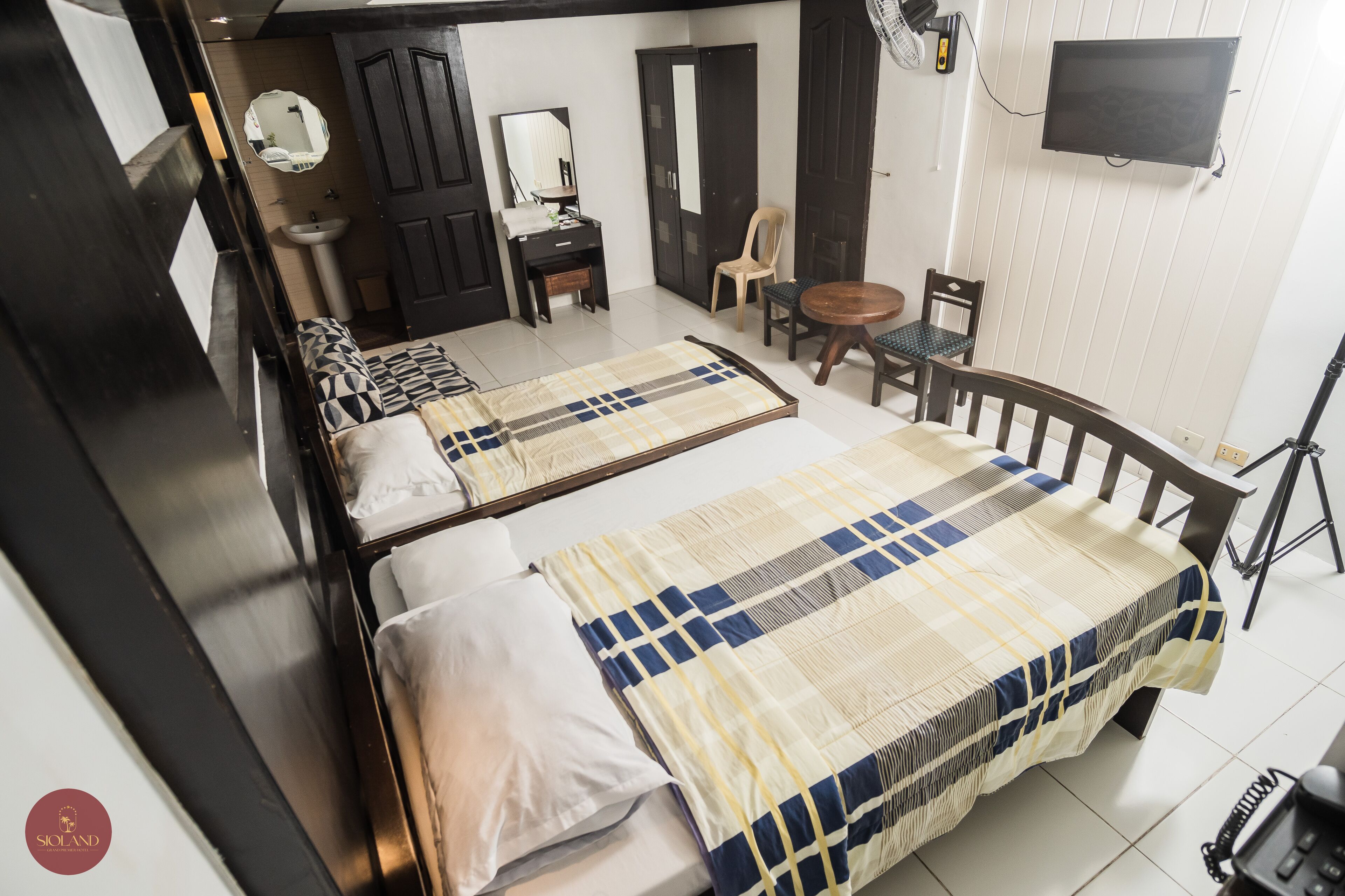A hotel room with two beds, a desk, a chair, a TV, and a telephone.