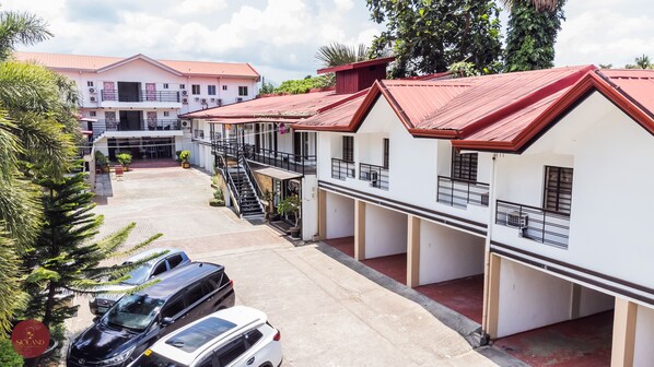 A row of white buildings with red roofs, a covered walkway, and parked cars. - Quezon Premier Hotel Lucena (Lucena)