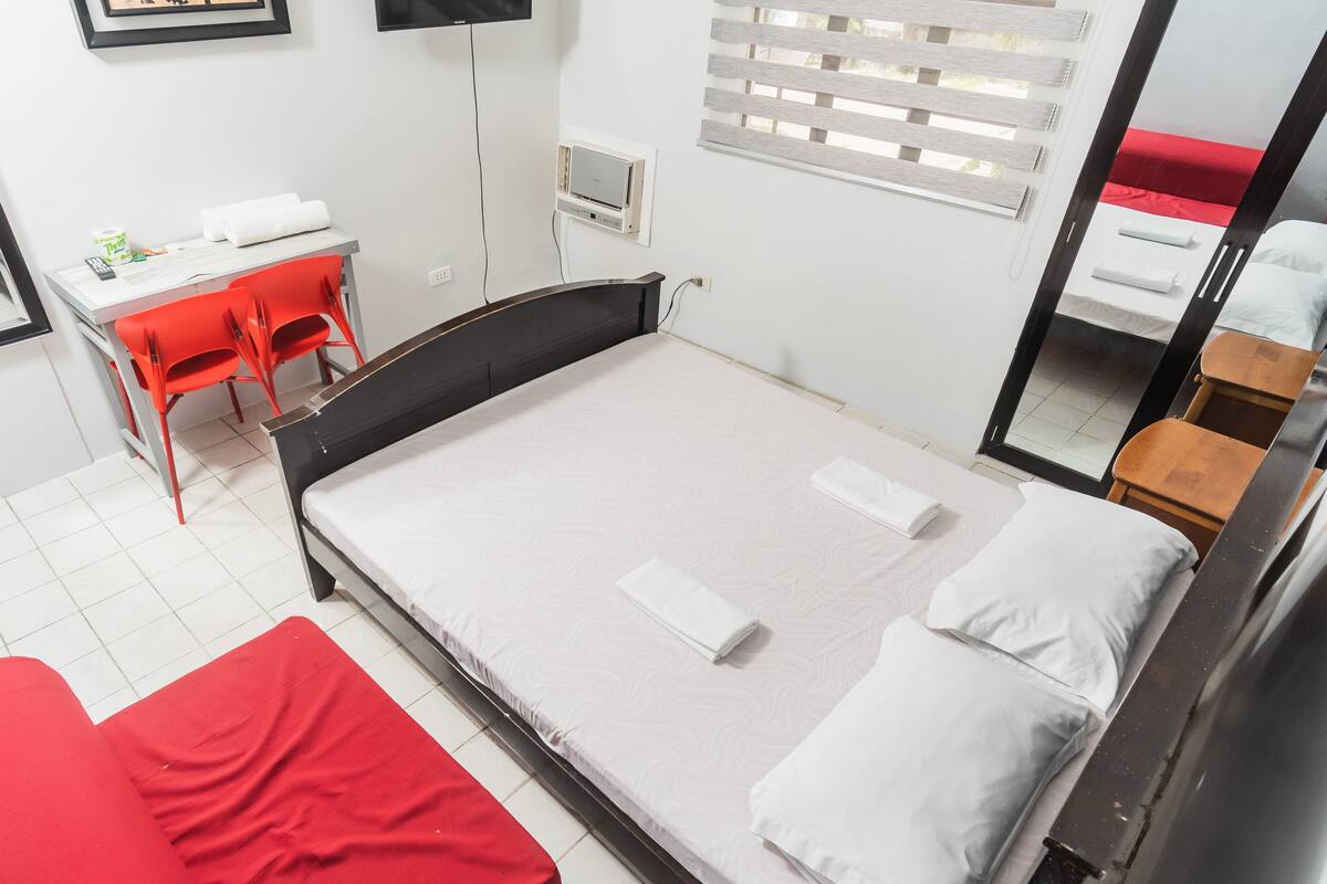 A hotel room with a bed, a desk, and a chair.