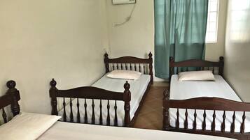 A room with two wooden beds, a window with curtains, and a wall-mounted air conditioner.