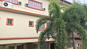 Un edificio de varios pisos con múltiples ventanas, algunas con marcos anaranjados, y varias unidades de aire acondicionado adheridas a las paredes exteriores.