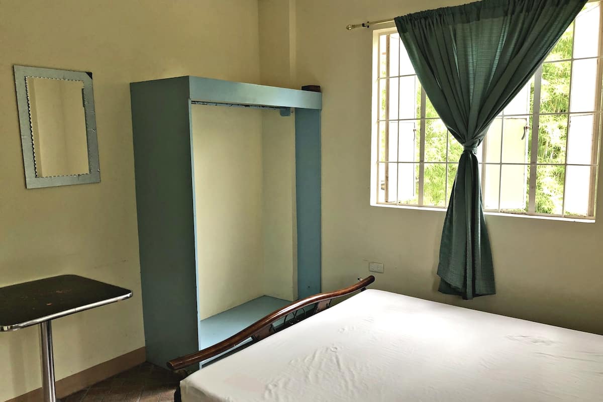 A room with a bunk bed, a small table, a mirror, and a window with curtains.