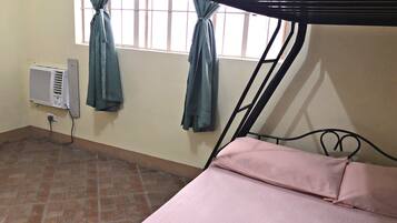Una habitación con una cama litera, una ventana con cortinas, un calentador de pared y suelo de baldosas.