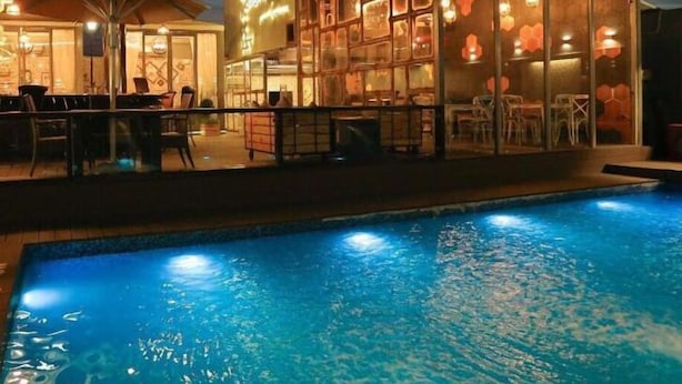 Un espace aménagé au bord de la piscine, avec un bar et un salon à l’intérieur d’une structure vitrée.