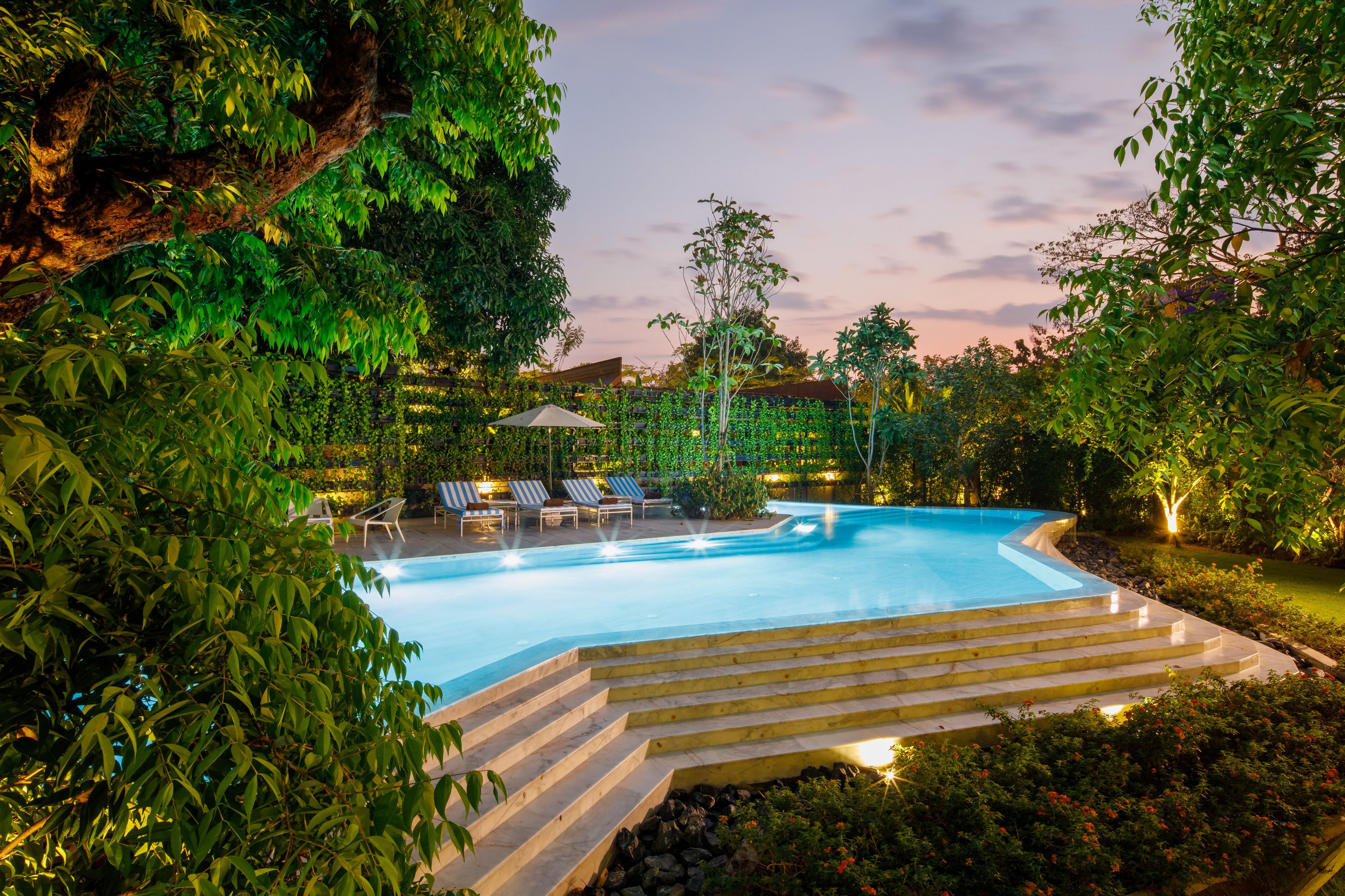 Una piscina al aire libre, sombrillas, sillones reclinables de piscina