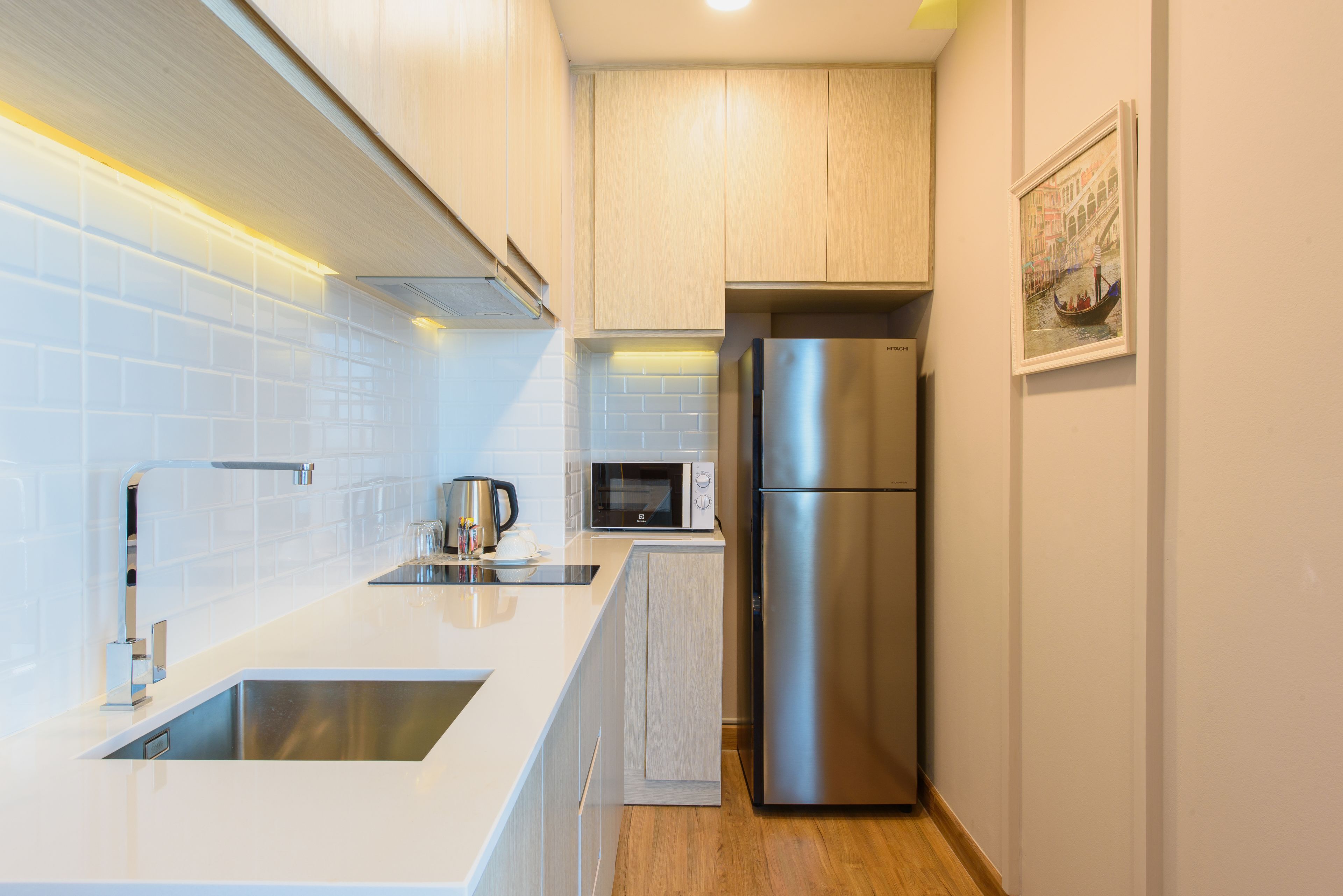 Une cuisine moderne dotée d’appareils électroménagers en acier inoxydable, d’un plan de travail blanc et de meubles de rangement en bois clair.