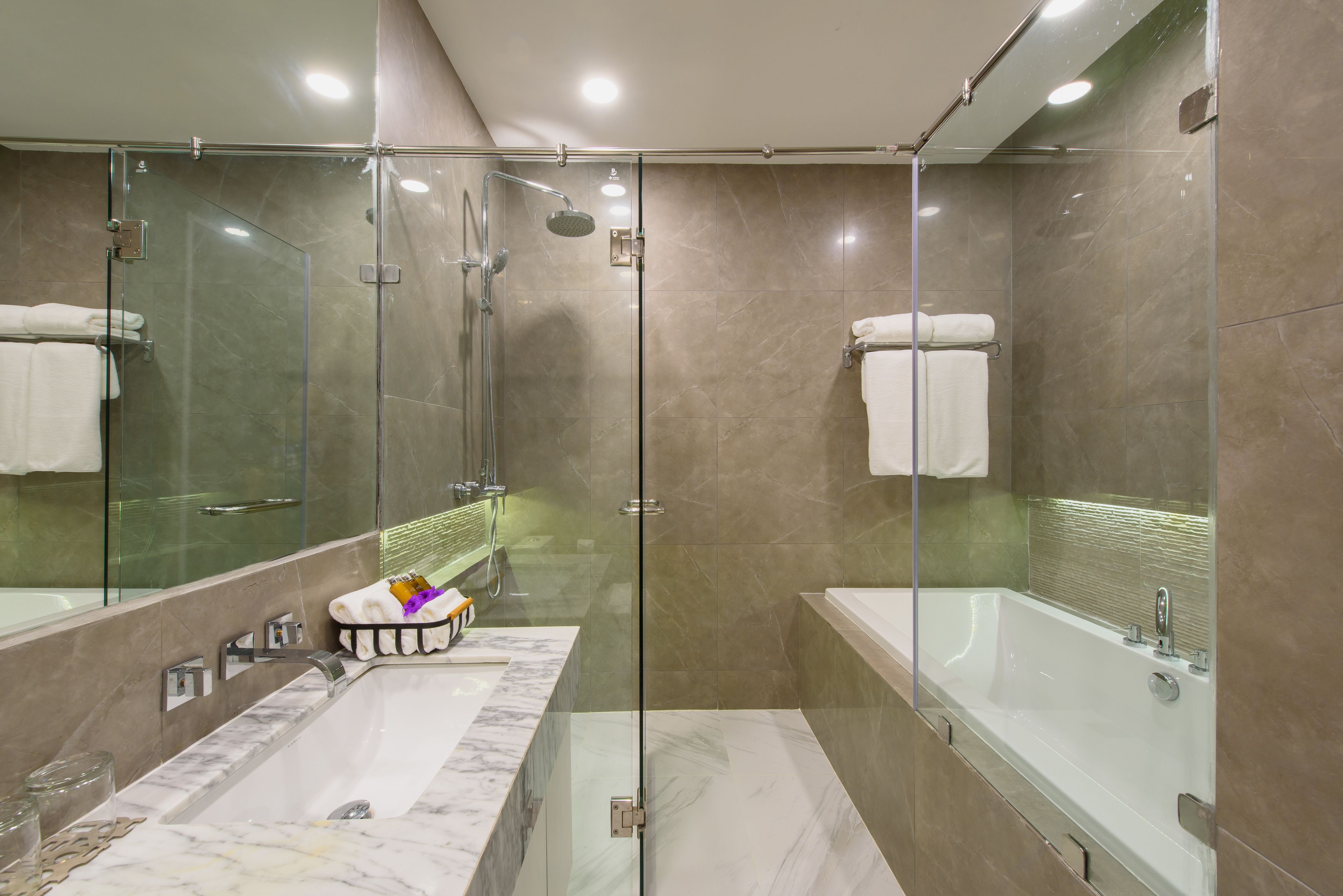 Un baño moderno con ducha envuelta en vidrio, una bañera grande y un lavabo de mármol.