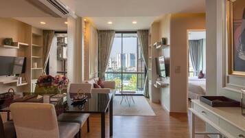 A modern living room with a dining area, a sofa, a TV, and a balcony with a city view.