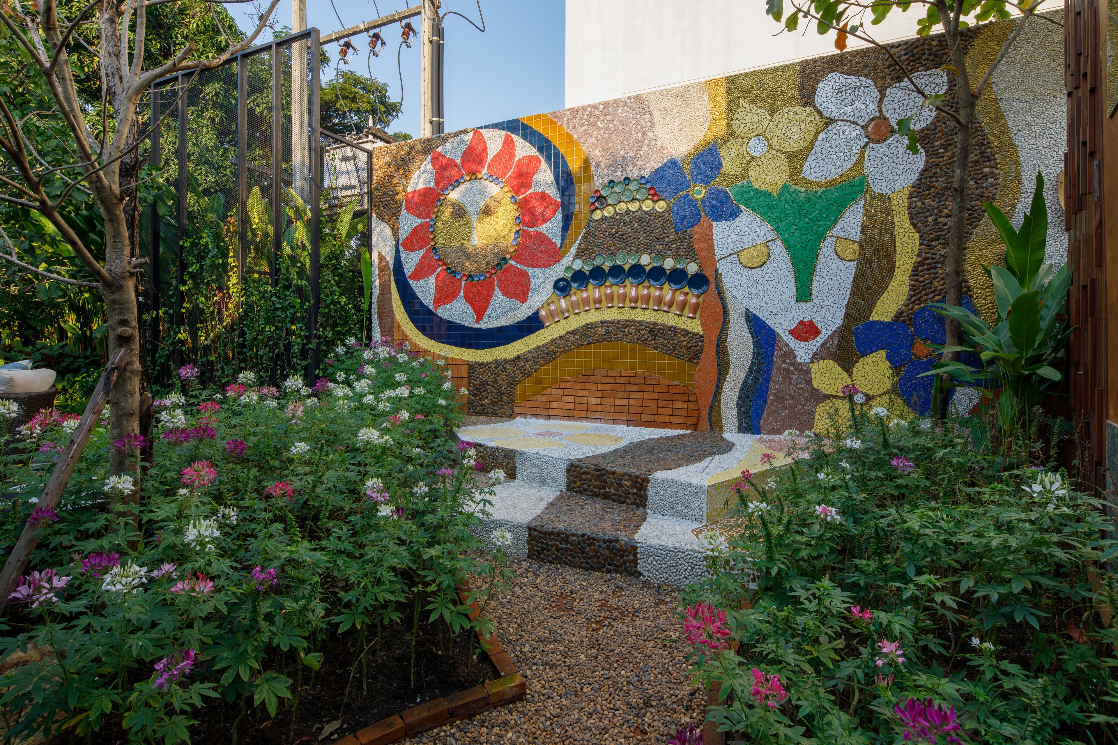 Una pared de mosaico con un diseño floral y escalones que conducen a una puerta.