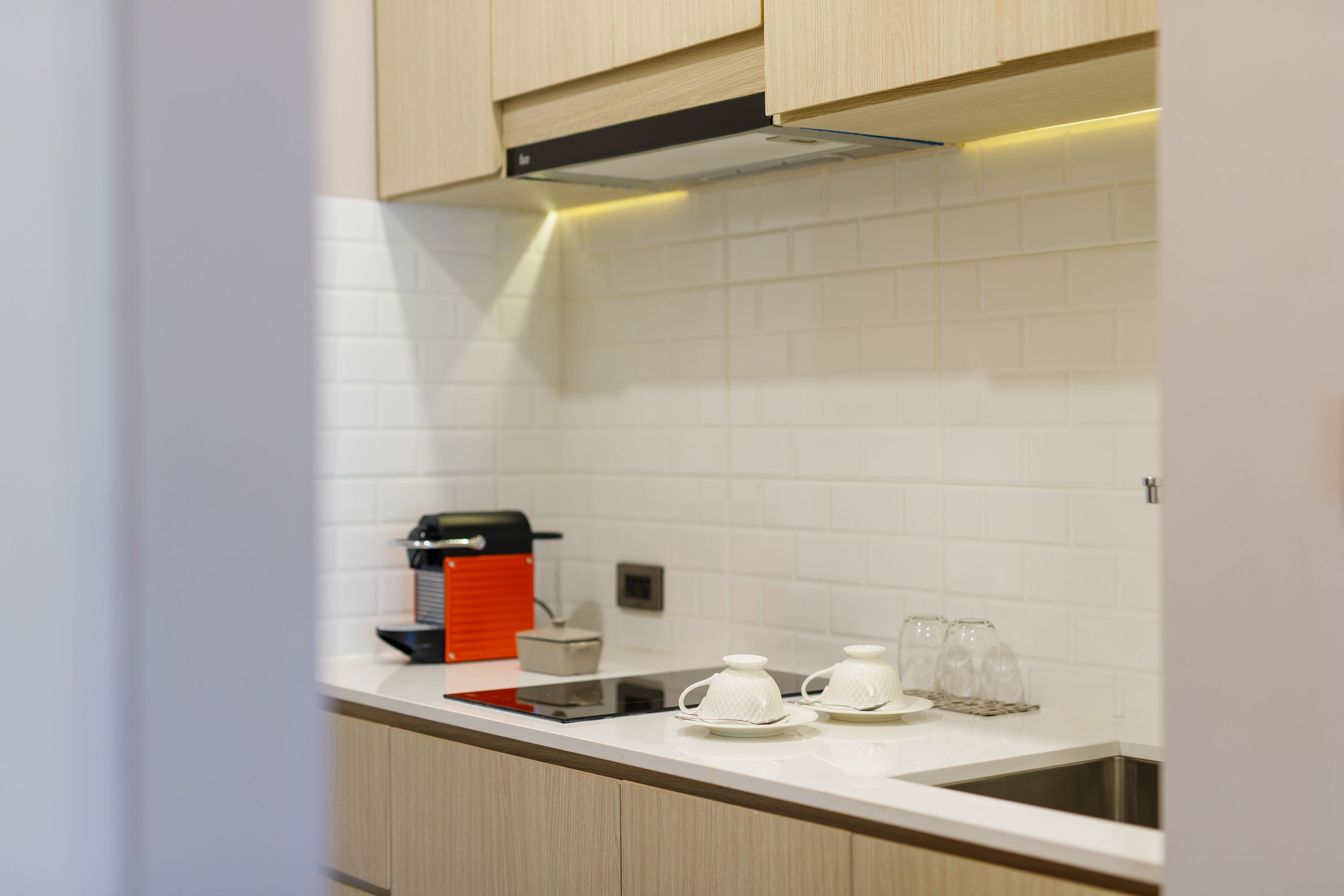 Cozinha moderna com azulejos brancos tipo metrô, pia de aço inoxidável e armários de madeira.