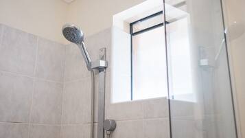 A shower with a handheld showerhead and a wall-mounted control.