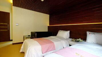 A hotel room with two beds, a wooden ceiling, a nightstand with a phone, and a door.