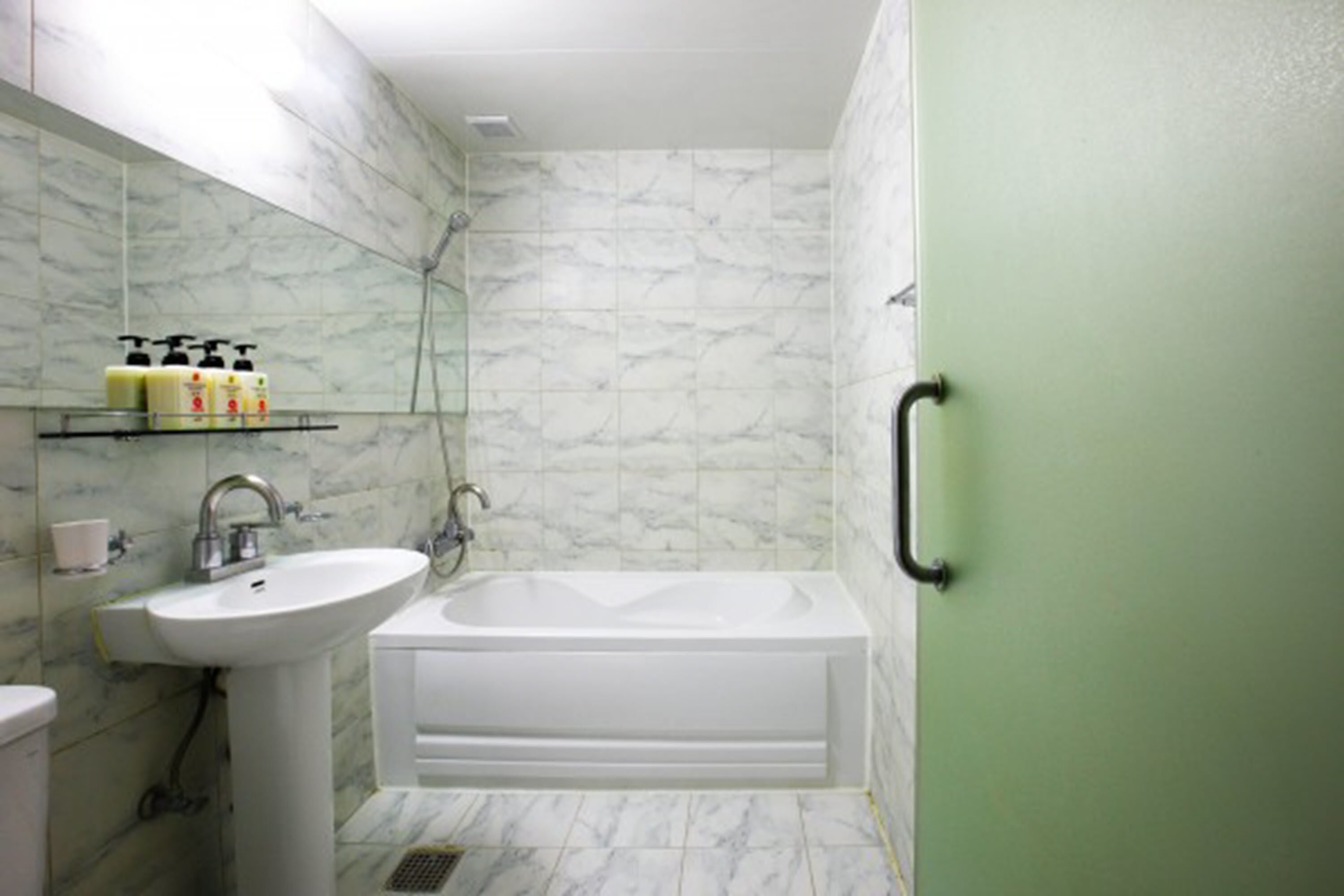 A bathroom with a white sink, a bathtub, and a shower. There are toiletries on a shelf.