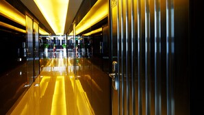 A modern hotel corridor with reflective floors, metallic doors, and bright overhead lighting. - Q Hotel (Paju)