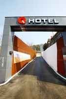 Entrada de hotel con un llamativo logotipo rojo con la letra 'Q' y la palabra 'HOTEL' encima.