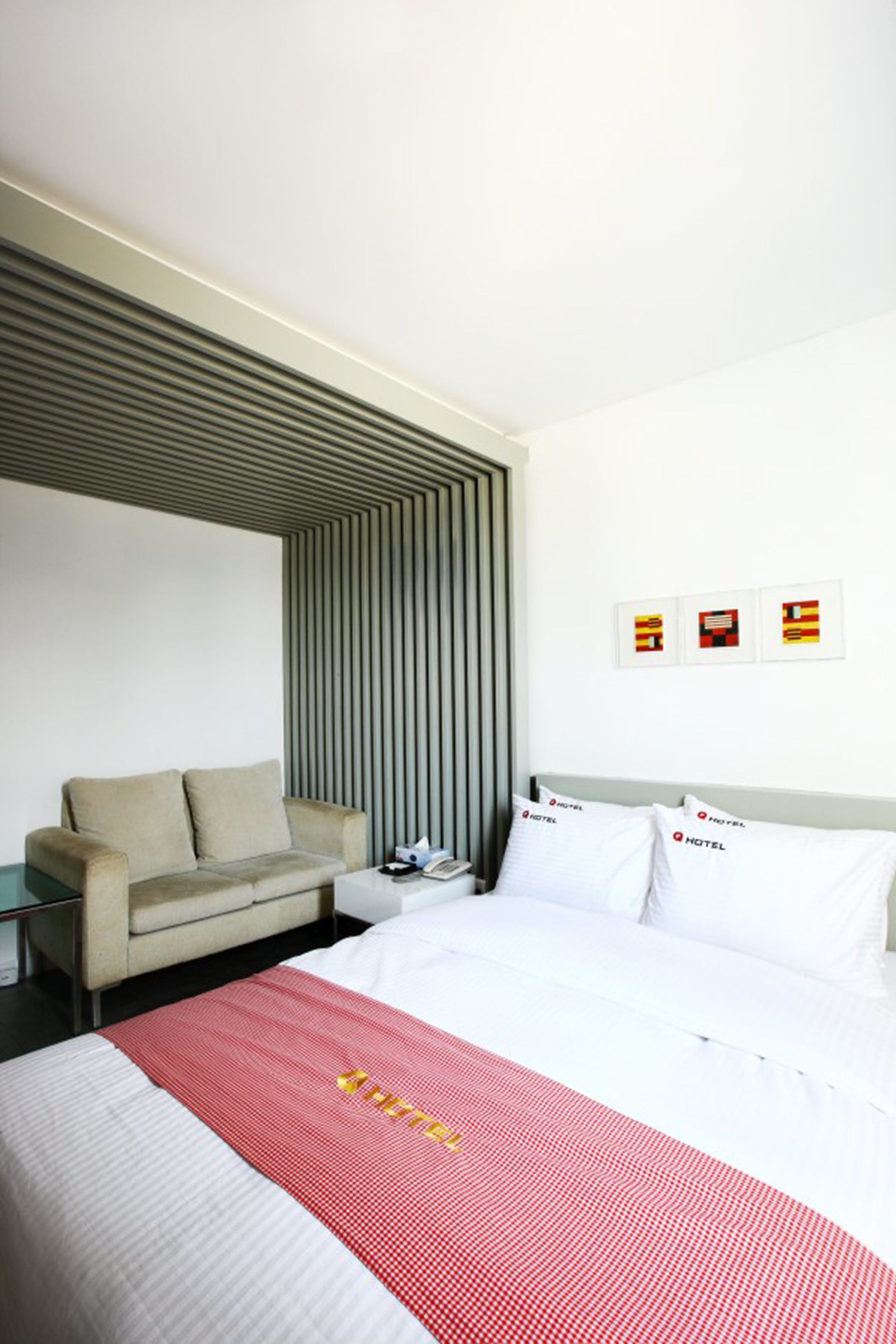 A modern hotel room with a bed, a sofa, and a nightstand.