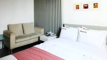 A modern hotel room with a bed, a sofa, and a nightstand.