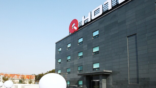 A modern hotel building with a prominent red logo on the roof and a flat facade. - Q Hotel (Paju)