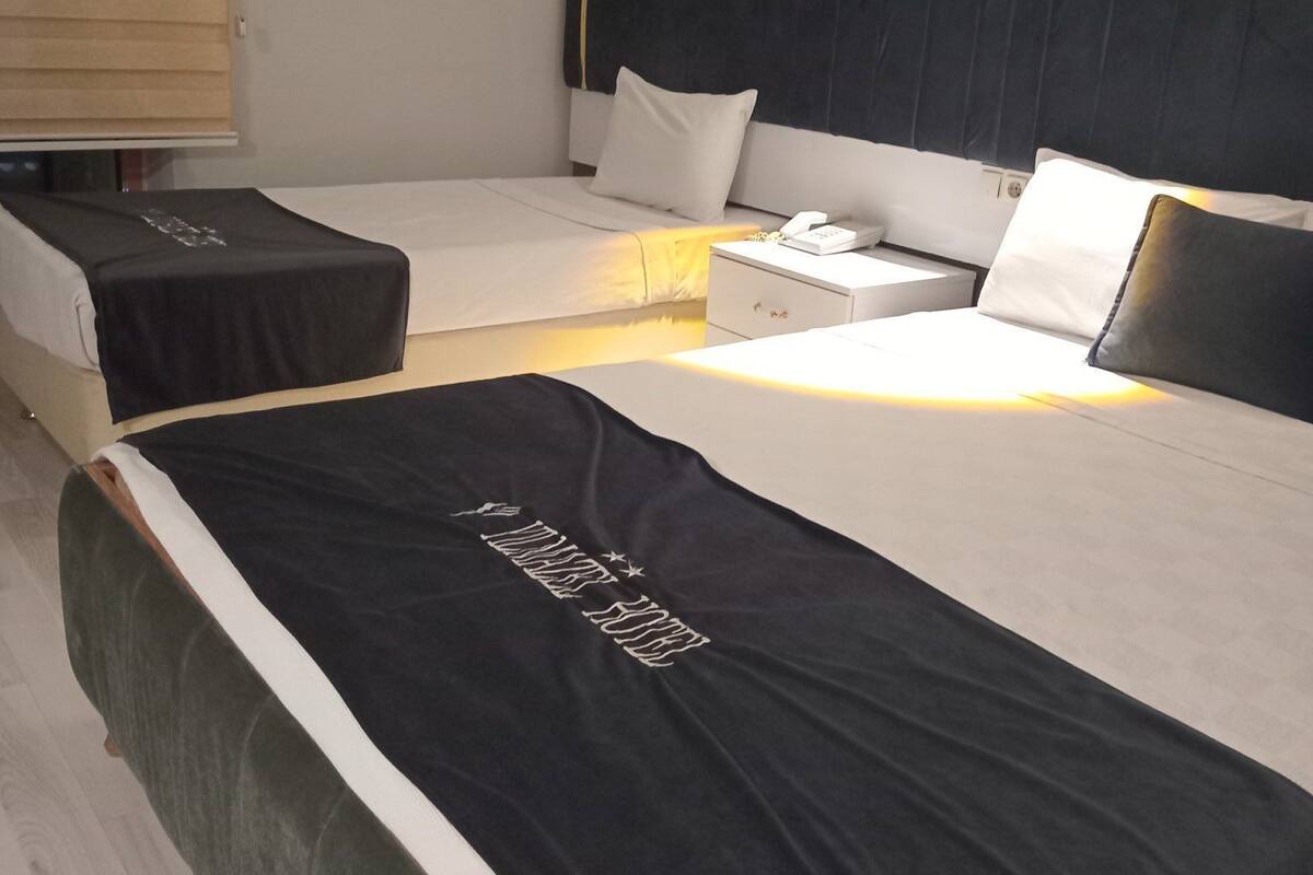 A hotel room with two beds, a nightstand, and a lamp.