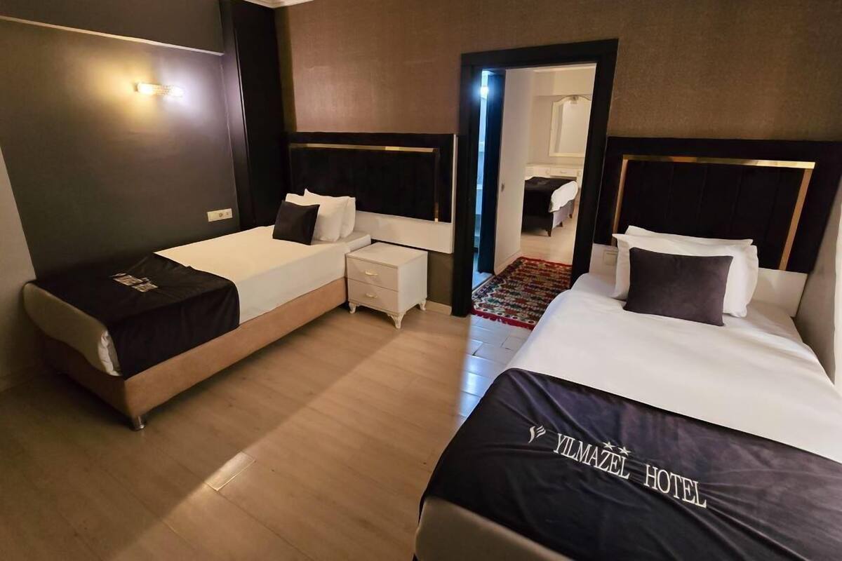 A hotel room with two beds, a nightstand, and a mirror.