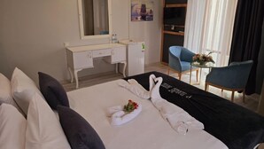 Une chambre d’hôtel avec un lit, un bureau, une chaise, un miroir et une fenêtre avec des rideaux.