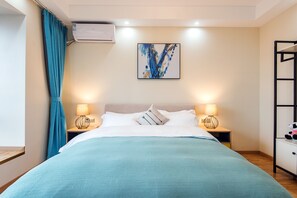 Un dormitorio con una cama, dos mesitas de noche con lámparas, un aire acondicionado instalado en la pared y un cuadro.