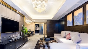A modern living room with a large flat-screen TV, a sofa, a coffee table, and a patterned rug. - Enjoy Stay YUNWEI Apartment (Chengdu)
