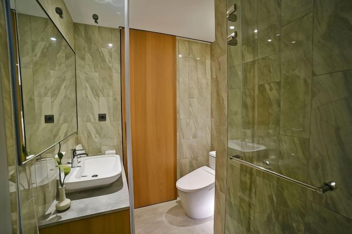 A modern bathroom with a glass shower enclosure, a white sink, and a toilet.