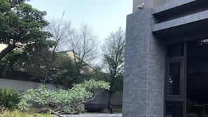 A modern building with a pool, surrounded by greenery and trees. - Yidear Hotel (New Taipei City)