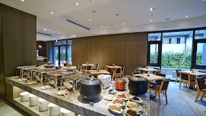 A buffet area with multiple food stations, tables, and chairs arranged for dining. - Yidear Hotel (New Taipei City)