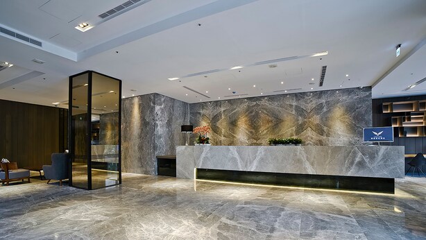 A modern lobby with a marble reception desk, seating area, and a large wall mural. - Yidear Hotel (New Taipei City)