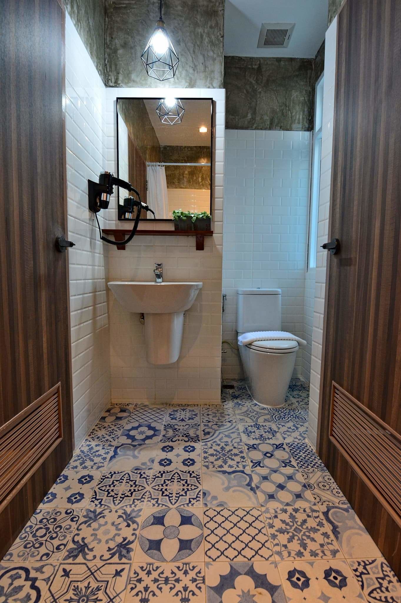 Une salle de bain avec un lavabo blanc, des toilettes et des carreaux de sol à motifs.
