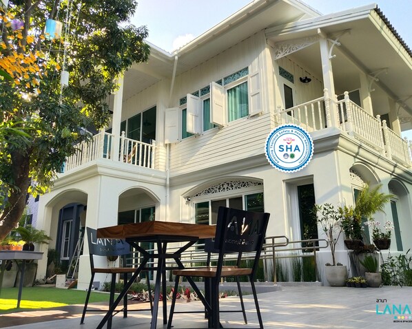 A two-story building with a balcony, a sign indicating it is a hotel, and a logo for the Thailand Safety & Health Administration.