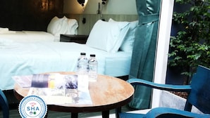 Ett hotellrum med två sängar, ett bord med vattenflaskor och utsikt över grönområden utanför.