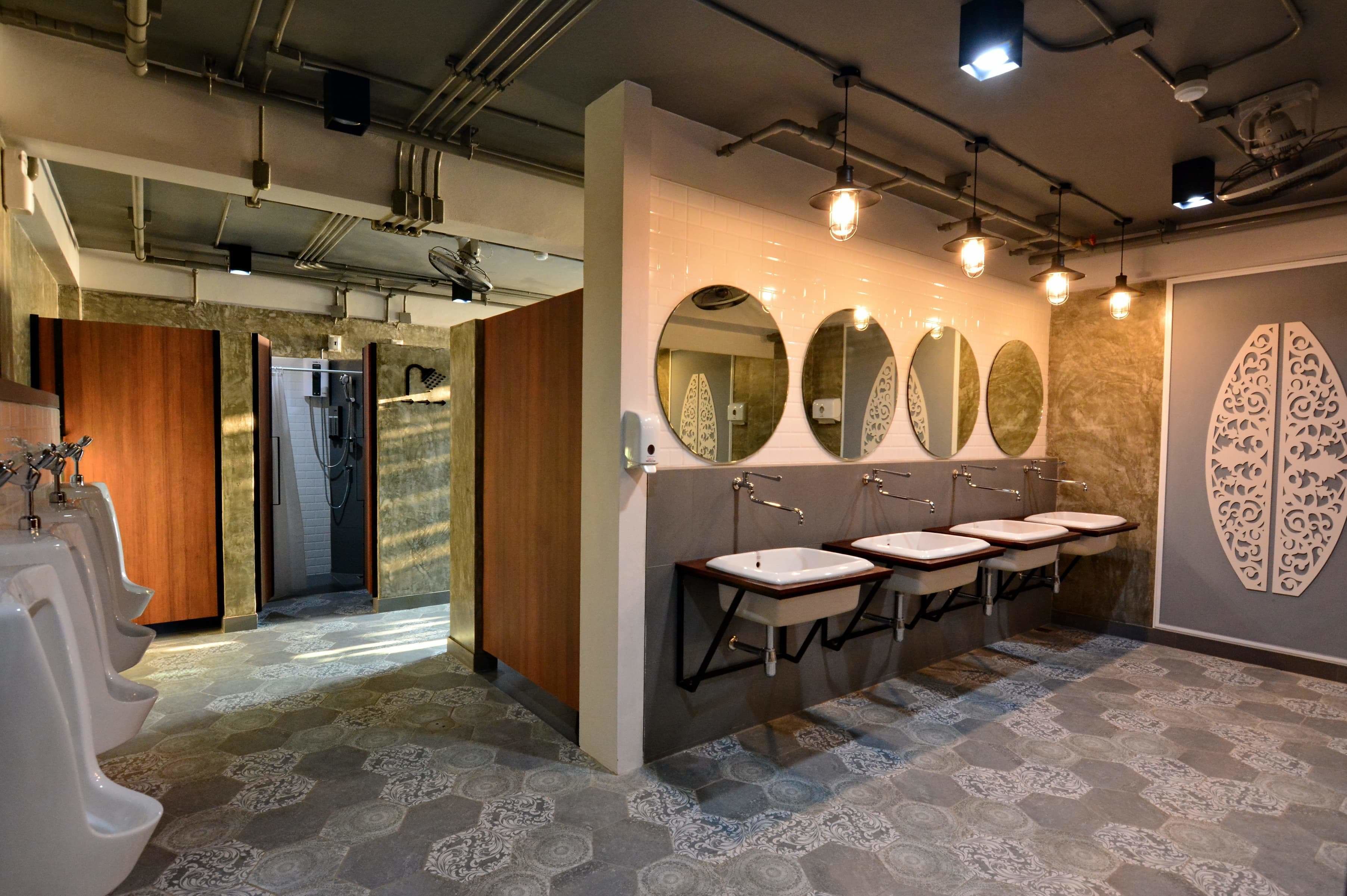 Un baño moderno con varios orinales, lavamanos y espejos.