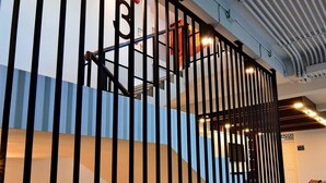 En modern interiör med ett svart metallräcke, en trappa och ett tak med linjära ljusarmaturer.