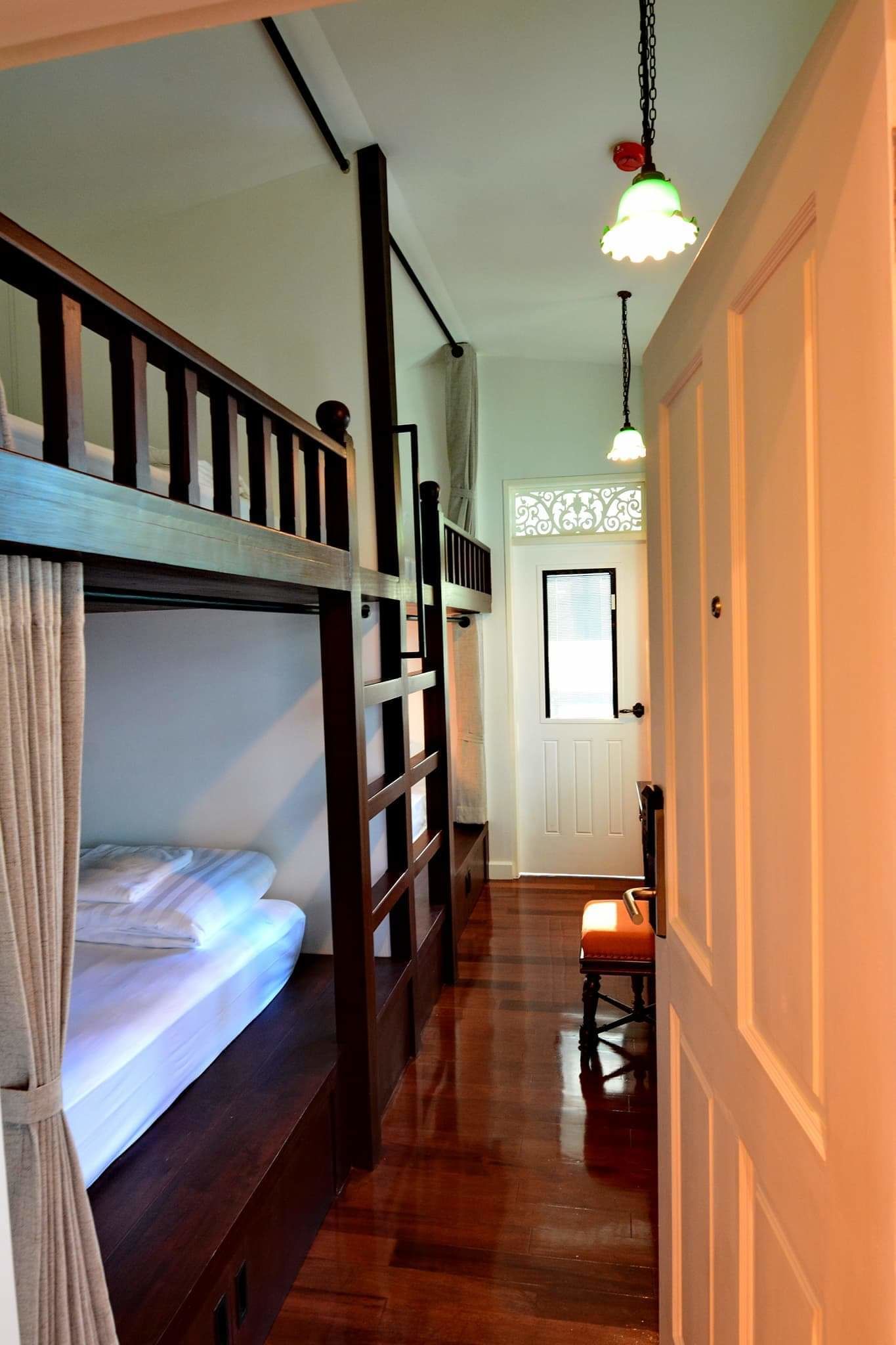 A narrow hallway with bunk beds on one side and a door at the end.
