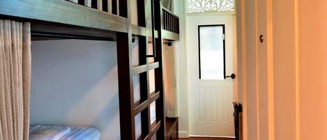 A narrow hallway with bunk beds on one side and a door at the end.