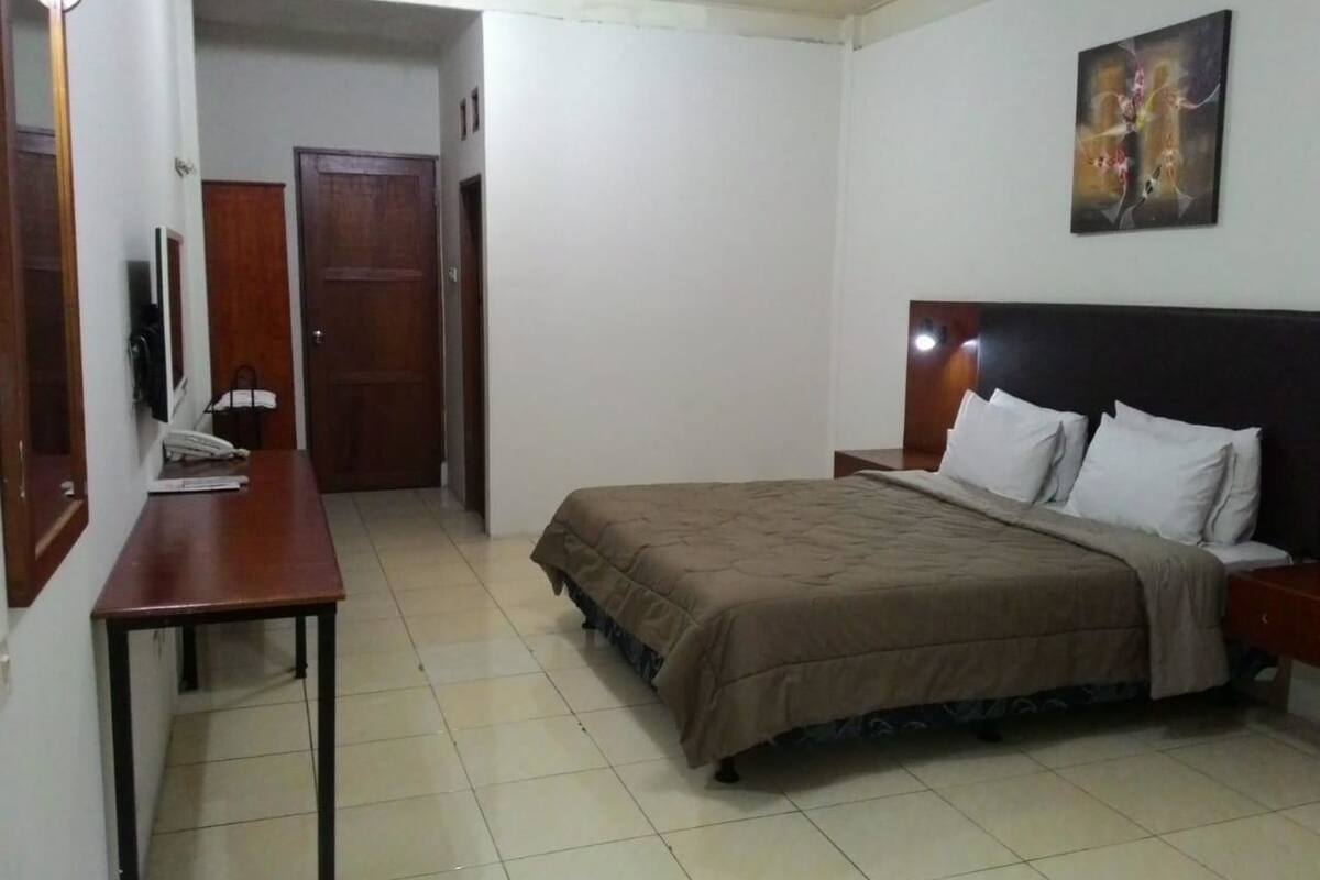 A bedroom with a bed, a desk, a chair, and a door.