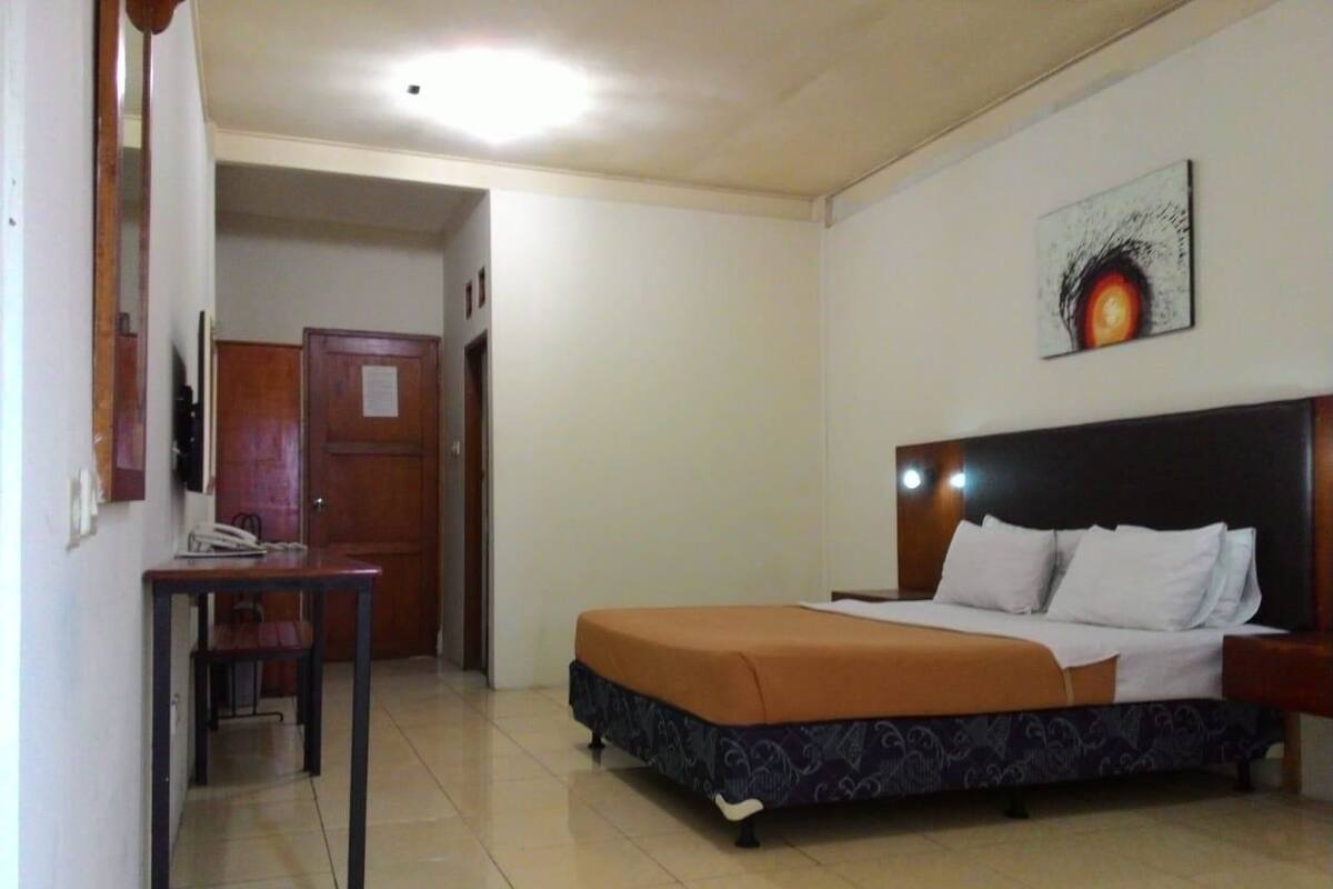 A hotel room with a bed, a desk, and a chair.
