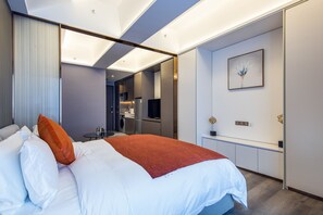 A modern hotel room with a large bed, a desk, and a kitchenette. - Gelade Residences Renhe Spring (Chengdu)