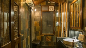 A bathroom with a stone wall, a wooden door, a sink, and a mirror.