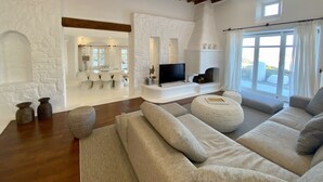 Uma sala de estar ampla com parede de pedra, lareira, televisão e uma grande janela.