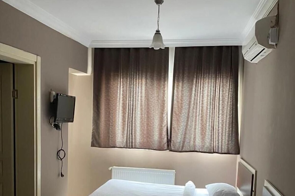 A bedroom with a bed, bedside table, and a wall-mounted TV.