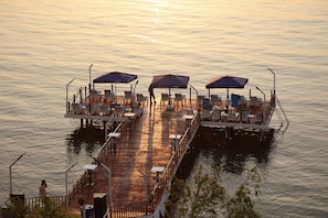 A floating restaurant with outdoor seating and umbrellas, surrounded by calm water.