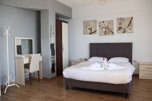 Un dormitorio con cama, escritorio, silla, perchero y obras de arte en la pared.
