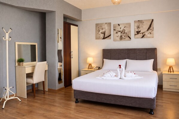 A hotel room with a large bed, bedside lamps, a desk with a chair, and artwork on the wall. - Grand Koru Otel Beach (Cinarcik)
