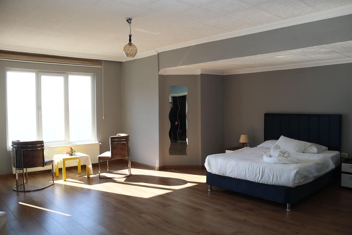 A bedroom with a large bed, a small table, two chairs, and a mirror.